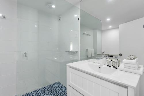 Un baño blanco con lavabo y ducha. en 1 Bedroom Apartment at The Queenslander, en Port Douglas