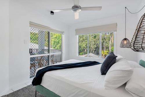 Un dormitorio blanco con una cama y dos ventanas. en 1 Bedroom Apartment at The Queenslander, en Port Douglas