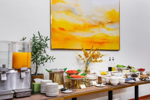 a table with plates and cups and a pitcher of orange juice at SureStay by Best Western Iconic Ari-Jatujak in Bangkok