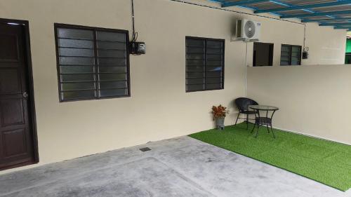 a room with a chair and a table with green grass at Cinta Homestay Satu UTHM in Parit Raja