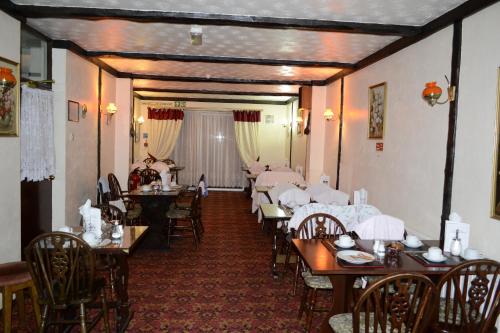 une salle à manger avec des tables, des chaises et un tissu de table blanc dans l'établissement Cranbrook Hotel, à Ilford