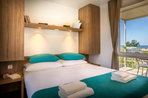 a bedroom with a large bed with blue and white pillows at Aminess Planet Camping Holiday Homes Maravea in Novigrad Istria