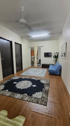a living room with a blue couch and a rug at Cinta Homestay Satu UTHM in Parit Raja