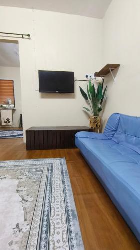 a living room with a blue couch and a flat screen tv at Cinta Homestay Satu UTHM in Parit Raja