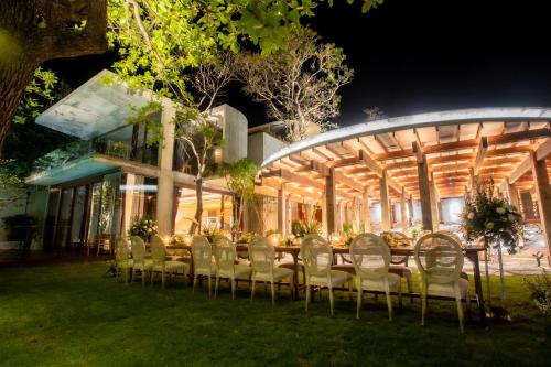 a long table with chairs in front of a building at Vows Villa Beachfront in Ban Bang Po