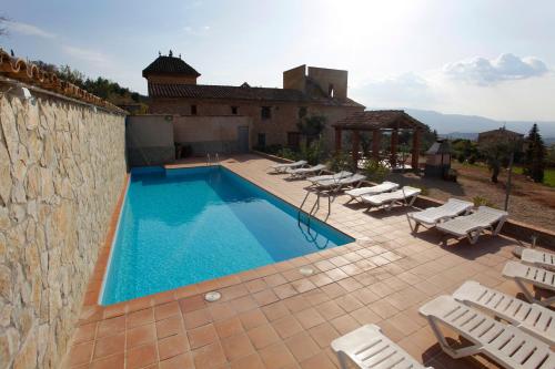 una piscina con sedie a sdraio e una casa di Mas la Planella Masia de Turismo Rural a Montblanc
