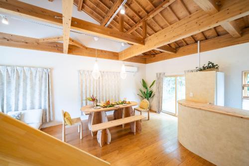 a dining room with a table and chairs and wooden ceilings at ファミリーハウスいさがわ in Isagawa