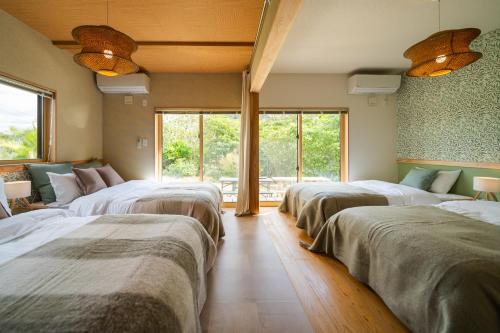 a row of beds in a room with windows at ファミリーハウスいさがわ in Isagawa