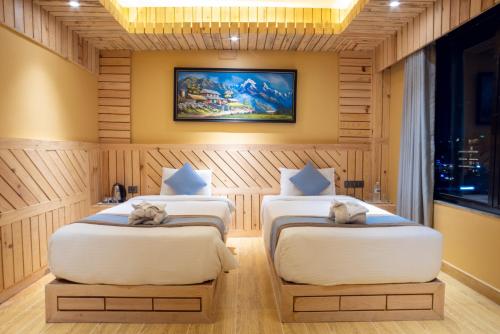 two beds in a room with a painting on the wall at Trekkers Inn Boutique Hotel Pokhara in Pokhara