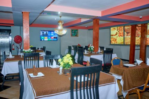 una sala da pranzo con tavoli e sedie e un lampadario di Elanacha Hotel ad Arusha