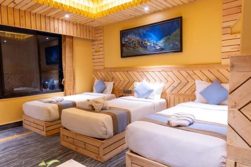 a room with three beds and a tv on the wall at Trekkers Inn Boutique Hotel Pokhara in Pokhara