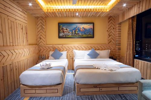 two beds in a room with wooden walls at Trekkers Inn Boutique Hotel Pokhara in Pokhara