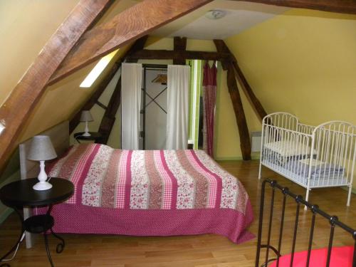 a attic bedroom with a bed and a crib at Entre Caps et Marais in Alembon