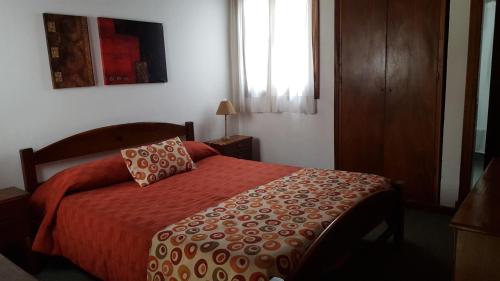 1 dormitorio con 1 cama con manta roja y ventana en Complejo Tekis en Mar del Plata