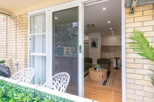 a sliding glass door on a balcony with chairs at Lucky's Coastal Retreat, 2 bedroom apartment and parking in Cronulla