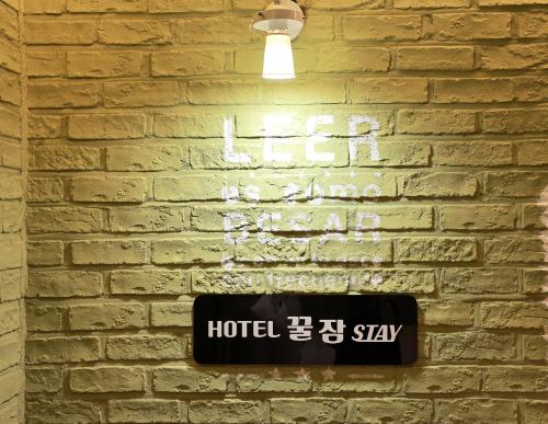 a hotel sign on a brick wall with a light at Hotel Kkuljam Stay in Jinju