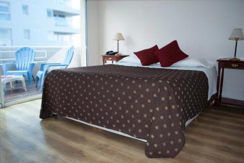 a bedroom with a bed with a brown blanket and chairs at Hotel Gran Madryn in Puerto Madryn