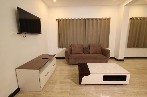 a living room with a couch and a tv at Aaditya Greens Near Nelaguli Panchyat Office in Kaglipur