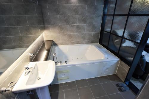 a bathroom with a bath tub and a sink at Hotel Kkuljam Stay in Jinju