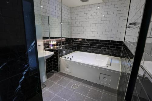 a bathroom with a bath tub and a sink at Hotel Kkuljam Stay in Jinju