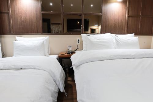 two beds in a hotel room with white sheets at Hotel Kkuljam Stay in Jinju