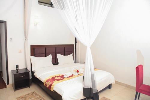 a bedroom with a bed with white sheets and a canopy at Hotel Kangaroo Bujumbura in Bujumbura