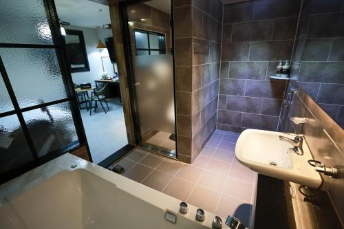 a bathroom with a tub and a sink and a shower at Hotel Kkuljam Stay in Jinju