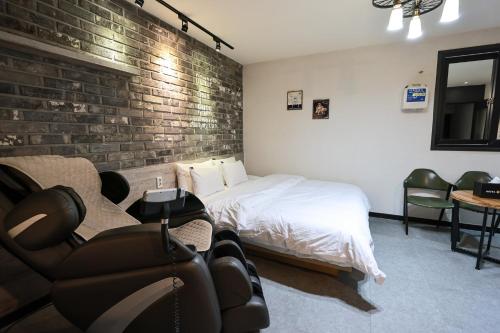 a bedroom with a bed and a brick wall at Hotel Kkuljam Stay in Jinju