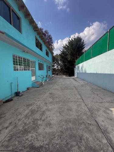 an empty parking lot next to a blue building at Glamping-Zingo in Santa Ana Jilotzingo