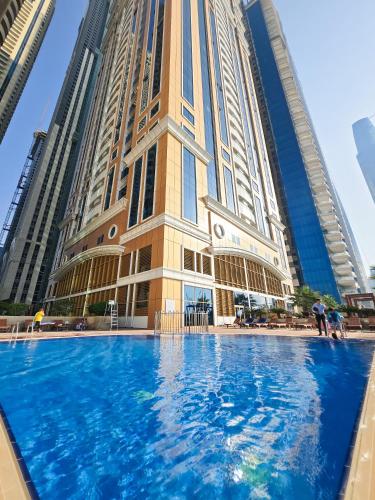 a building with a blue pool in front of it at Fabulous 1BR in Dubai Marina near Beach With Sea Views in Dubai