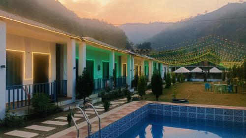 a hotel with a swimming pool and a view of the mountains at Amrah Resort in Bairāgarh