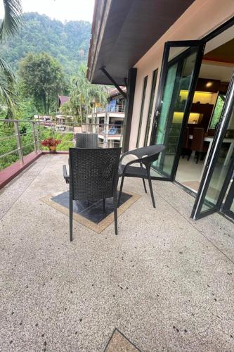a black chair sitting on a patio near a building at Kamala Villa Hill in Kamala Beach