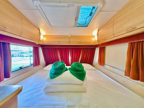 two green towels sitting on a bed in a caravan at Beach House Pool Villa in Na Jomtien
