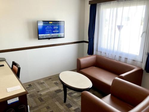 a waiting room with a couch and a table and a tv at Toyoko Inn Okayama eki Higashi guchi in Okayama