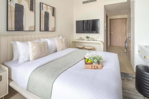 a bedroom with a large white bed with a plant on it at Frank Porter - Azizi Riviera 1 in Dubai