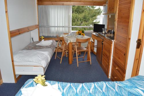 a room with two beds and a table and a kitchen at Residence Il Vigo di Marilleva in Marilleva