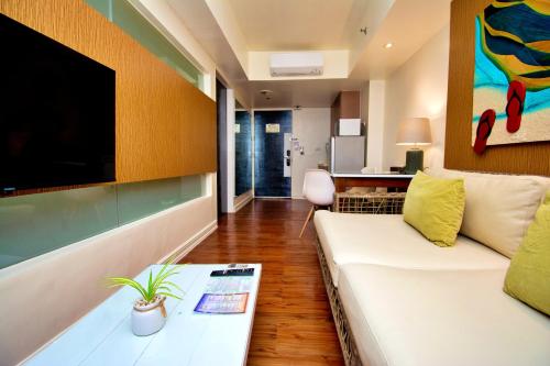 a living room with a white couch and a tv at Ferra Premier by JG in Boracay