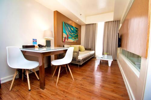 a hotel room with a table and chairs and a couch at Ferra Premier by JG in Boracay