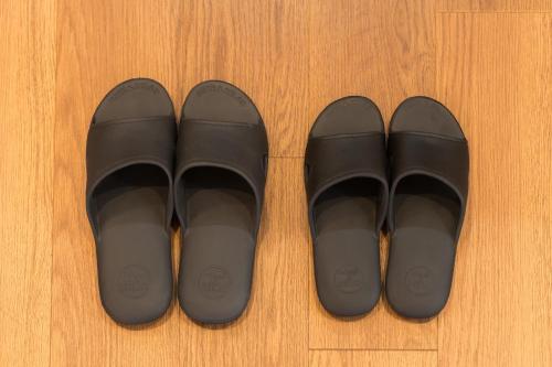 two pairs of black shoes on a wooden floor at Flower Base Fuji in Muromimachi