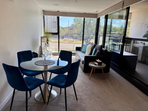 a living room with a table and blue chairs at Midnight Luxe 1BR 1Bath Apartment 104 in the heart of Braddon Pool Sauna Secure Parking Wine WiFi in Canberra