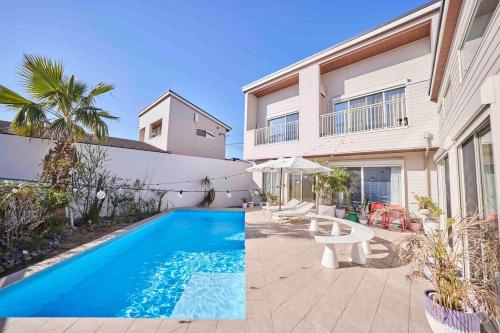 a swimming pool in front of a house at Aqua Villa with Pool, Sauna, and 100 inch 4K Projector, 5-minute walk from Fujitsu Park Sea in Futtsu