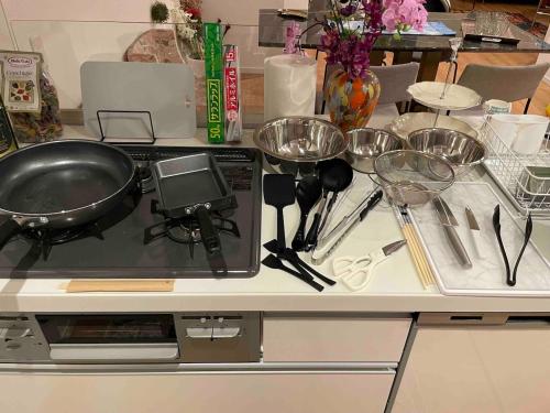 a counter with a frying pan and other kitchen utensils at Aqua Villa with Pool, Sauna, and 100 inch 4K Projector, 5-minute walk from Fujitsu Park Sea in Futtsu