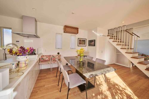 a kitchen with a table and chairs and stairs at Aqua Villa with Pool, Sauna, and 100 inch 4K Projector, 5-minute walk from Fujitsu Park Sea in Futtsu
