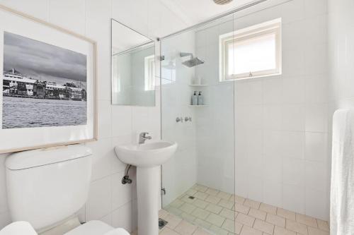 Un baño blanco con lavabo y ducha. en The Sunlit Fern - Minutes from Dining & Coastline, en Sídney