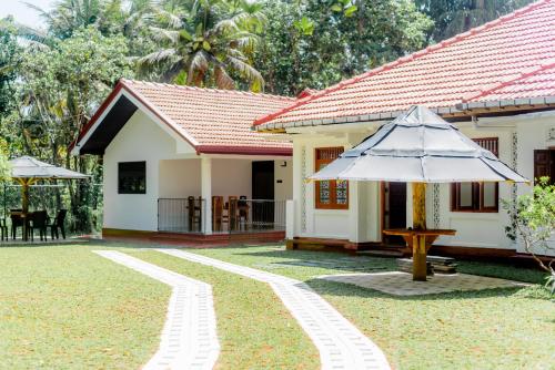 a house with an umbrella in the yard at Villa Utopia Mirissa in Mirissa