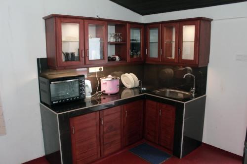 a kitchen with wooden cabinets and a sink and a microwave at Villa Utopia Mirissa in Mirissa