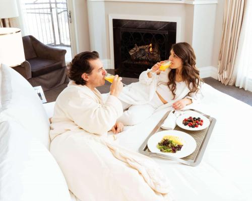 a man and woman sitting on a bed drinking orange juice at Waldorf Astoria Chicago in Chicago