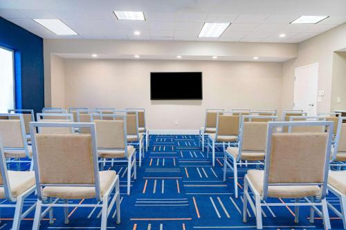 an empty room with chairs and a flat screen tv at Hampton Inn Baton Rouge - Denham Springs in Denham Springs