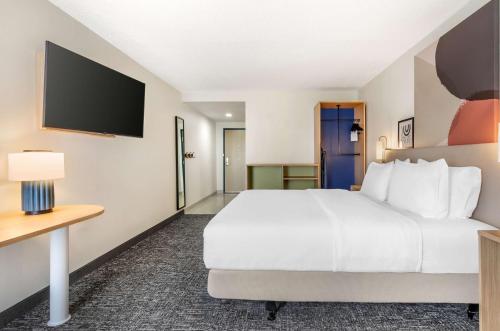 a hotel room with a bed and a flat screen tv at Spark By Hilton Roanoke Airport in Roanoke