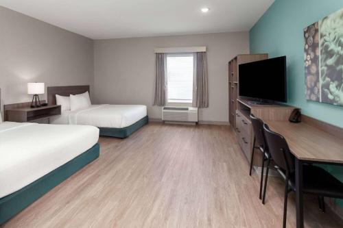 a hotel room with two beds and a desk and a television at ECHO Suites Extended Stay by Wyndham Madison in Madison